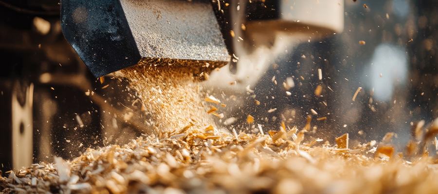 Mulch, an example of vegetation waste, are pictured shooting out of a wood chipper.